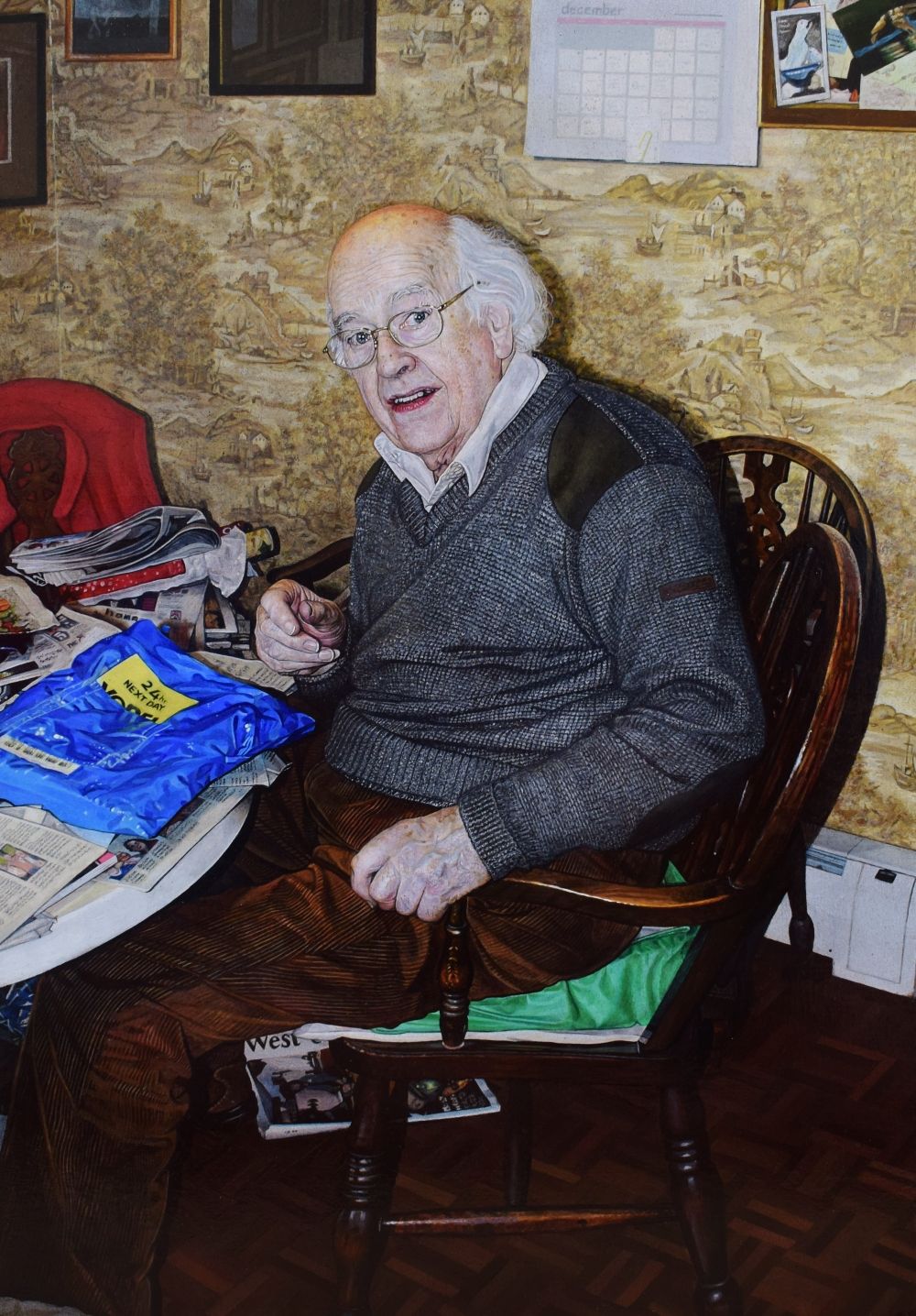 A man sitting a table looking at the camera surrounded by newspapers