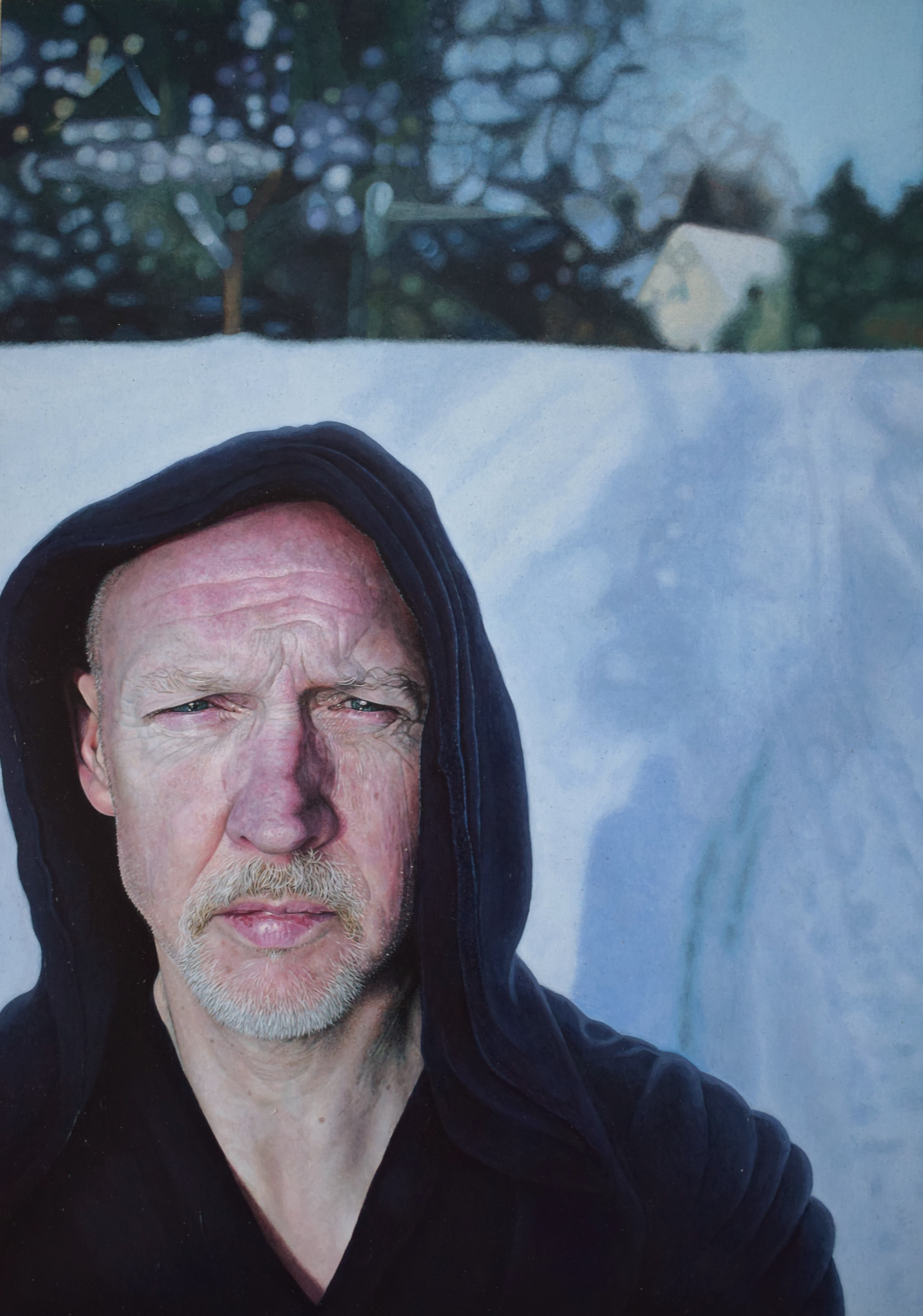 A hooded middle-aged man staring straight ahead