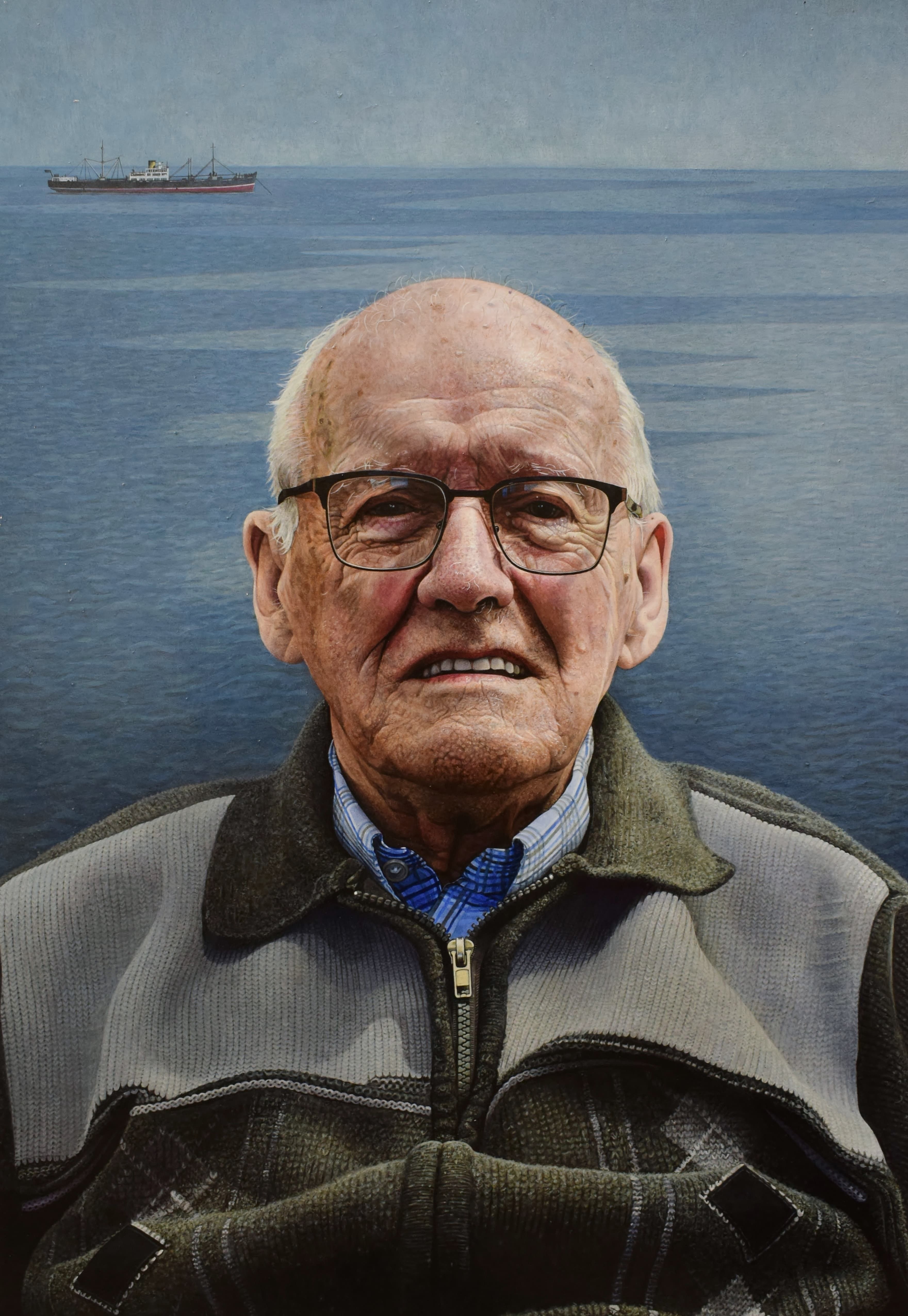 An older man pictured against a marine backdrop with a ship on the horizon 
